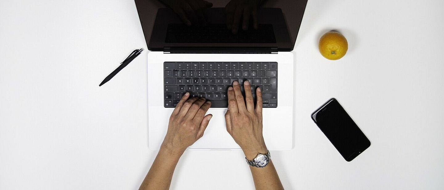Zwei Hände tippen auf einer Laptop-Tastatur