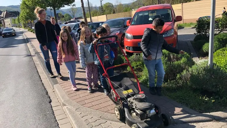 Die KiTa-Kinder mit dem Rasenmäher auf dem Weg in den KiTa-Garten.
