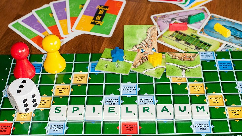 Verschiedene Spiele ausgebreitet, mit Würfel, Spielfiguren und Karten