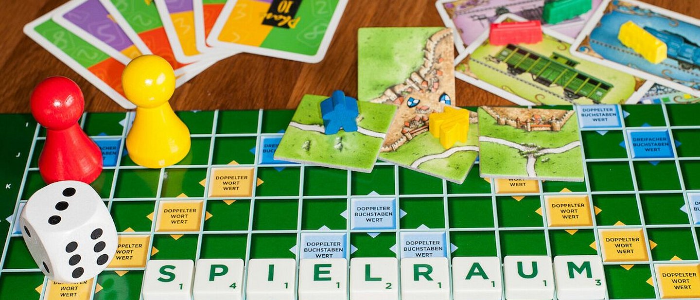 Verschiedene Spiele ausgebreitet, mit Würfel, Spielfiguren und Karten