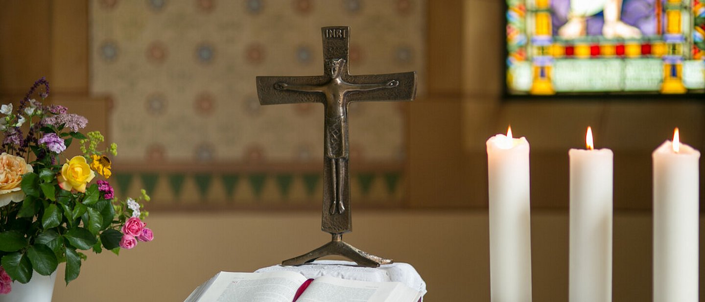 im Hintergrund buntes Glasfenster und Blumengesteck.