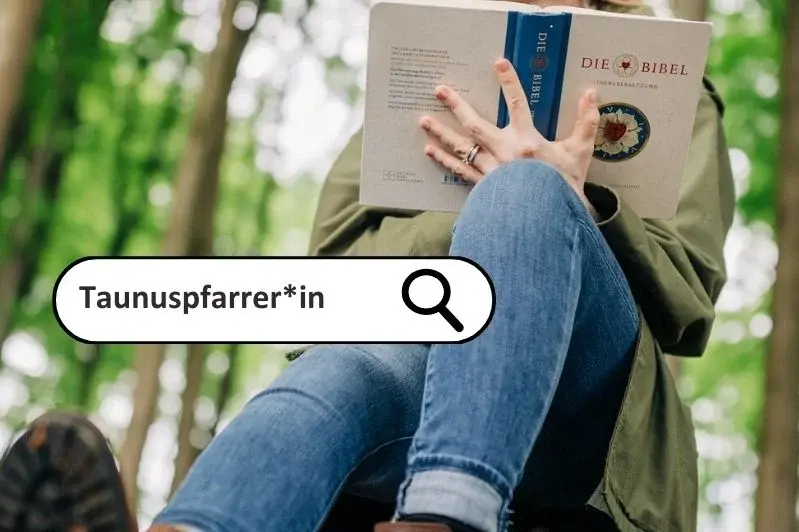 Eine Frau in Jeans sitzt auf einem Stein im Wald und liest in der Lutherbibel. Man sieht den Körper aus einer Perspektive von den Füßen her und nur bis zum Oberkörper. Das Gesicht ist von der Bibel verdeckt. 