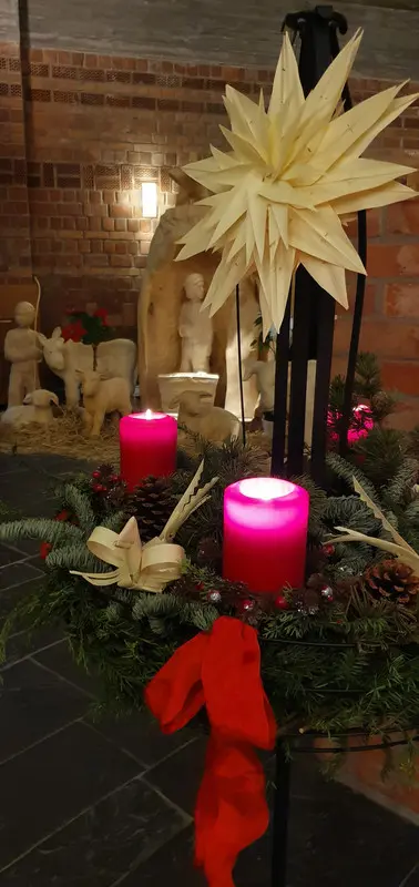 Adventskranz und Krippe im Hintergrund