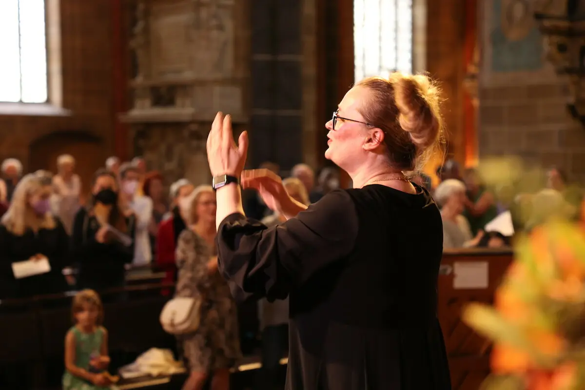 Frauen und Männer singen und stehen, in einer Kirche, zusammen.