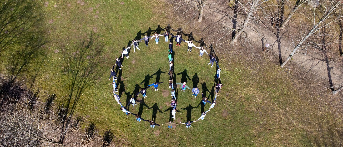 Man sieht eine Luftaufnahme von jugendlichen Konfirmanden die ein Peace Zeichen bilden.