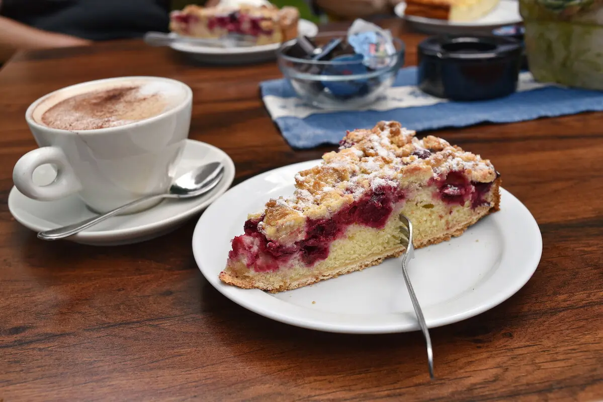 Ein Stück Kirsch-Streuselkuchen und ein Cappuccino.