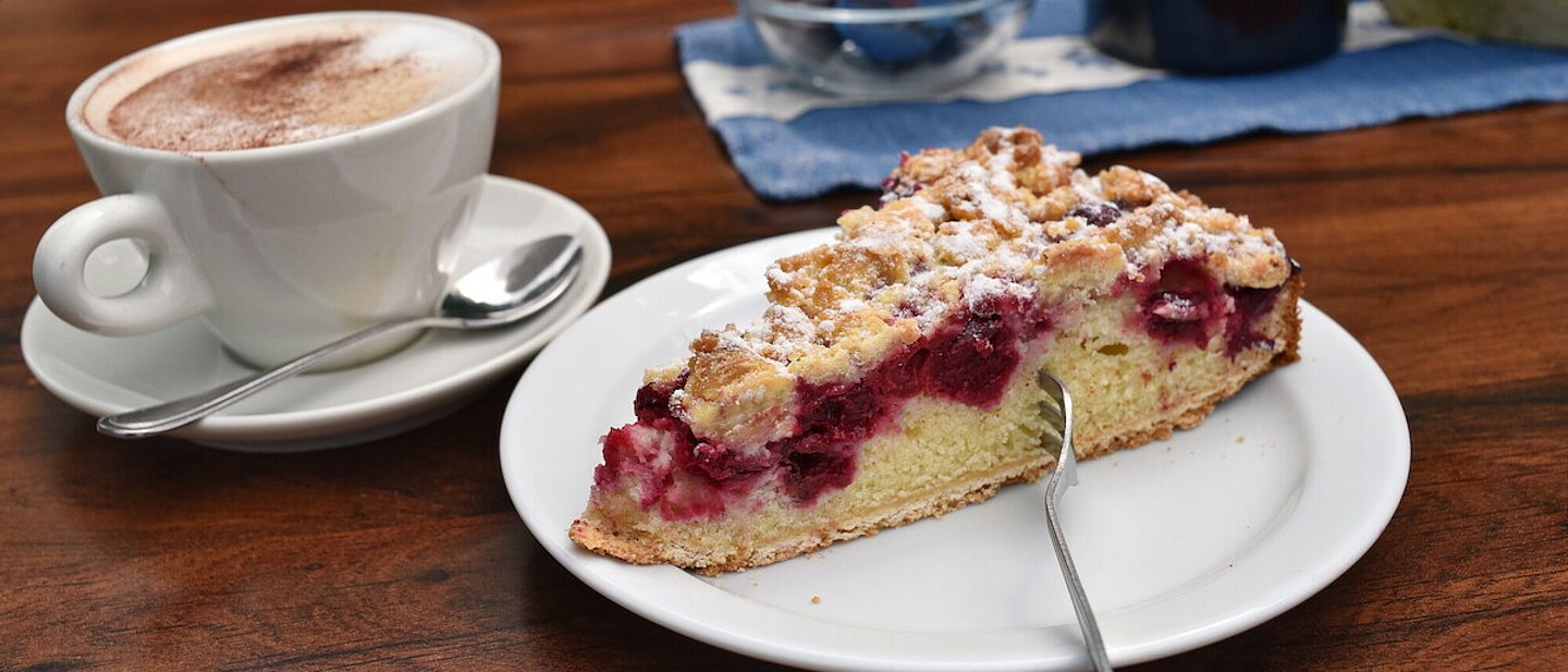 Ein Stück Kirsch-Streuselkuchen und ein Cappuccino.