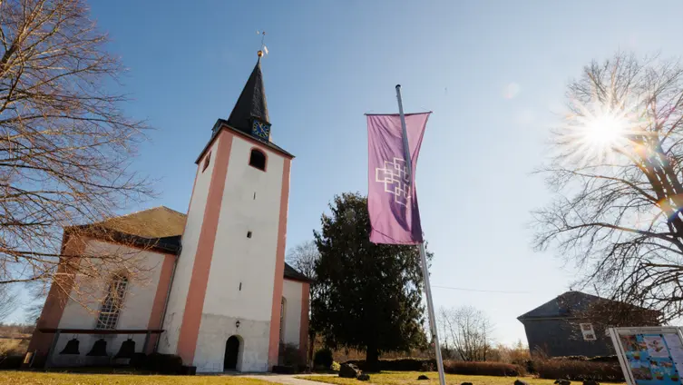 Ev. Kirche Neunkirchen im Westerwald im Sonnenschein mit EKHN-Fahne
