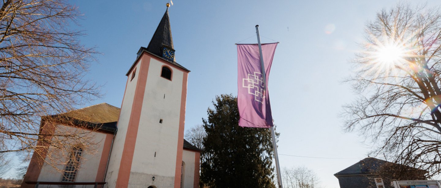 Ev. Kirche Neunkirchen im Westerwald im Sonnenschein mit EKHN-Fahne
