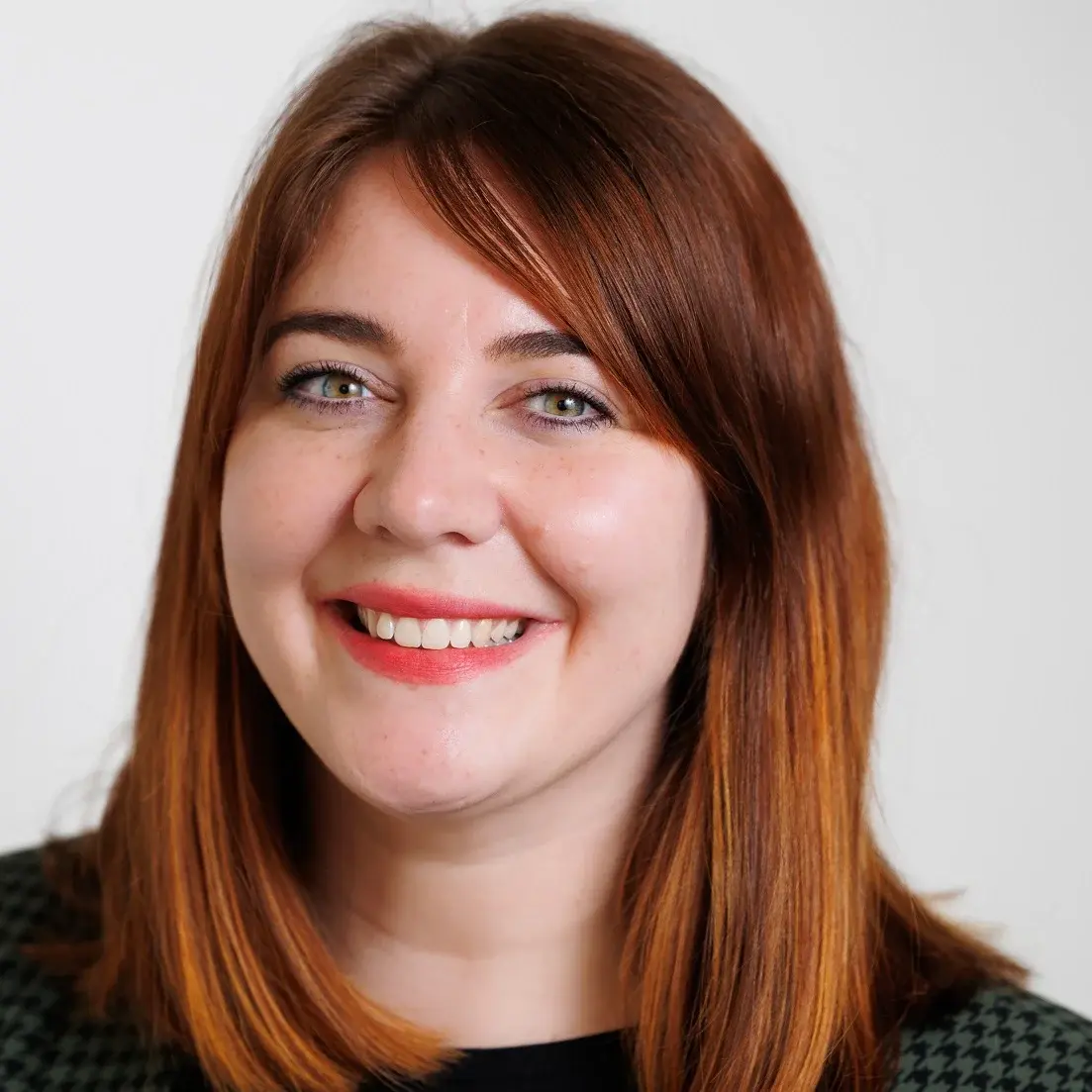 Junge Frau mit roten Haaren und Lippen und grünem Blazer