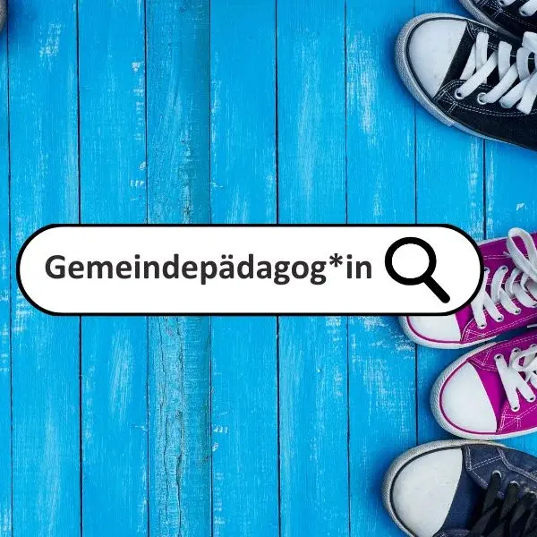 Ein Suchfeld mit dem Wort "Gemeindepädagog*in" und dem Ikon einer Lupe vor einem Hintergrund aus blau gestrichenen Holzbalken. Am rechten Bildrand sind die Anschnitte von Sneakers zu sehen. 