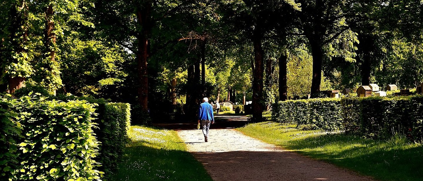 Trauernder Mann geht über einen Friedhof, ein Bild mit Licht und Schatten