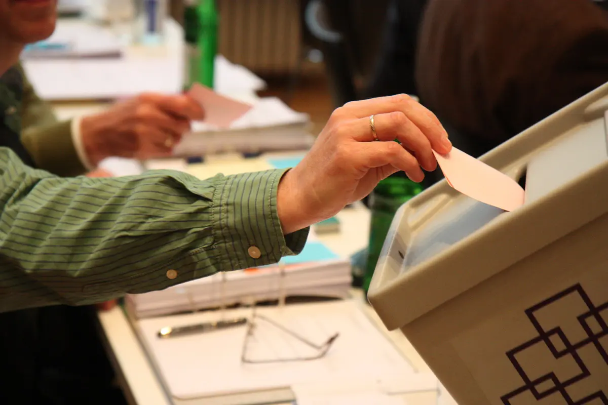 Hand legt Stimmzettel in Wahlurne