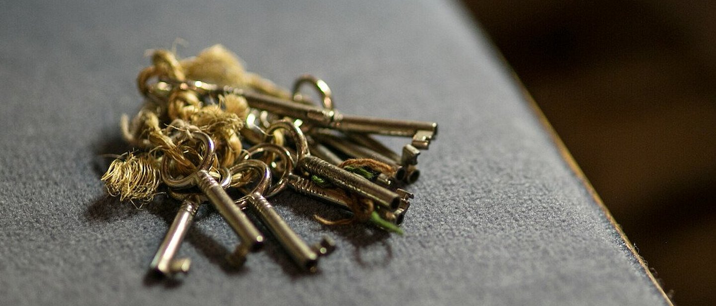 Schlüsselbund liegt auf grauem Stoff, vrmtl. Sitzpolster der Kirchenbank