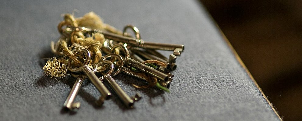 Schlüsselbund liegt auf grauem Stoff, vrmtl. Sitzpolster der Kirchenbank