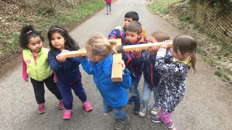Das Foto zeigt die Kinder der Kindertagesstätte die ein Holzkreuz auf ihren Schultern tragen.