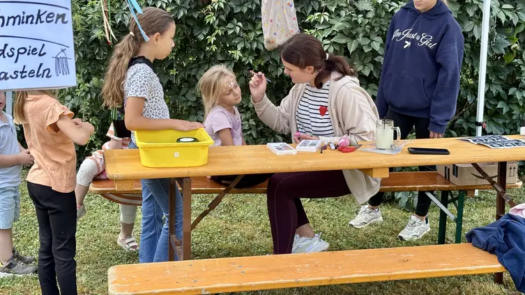 ein älteres Mädchen schminkt ein jüngeres Kind