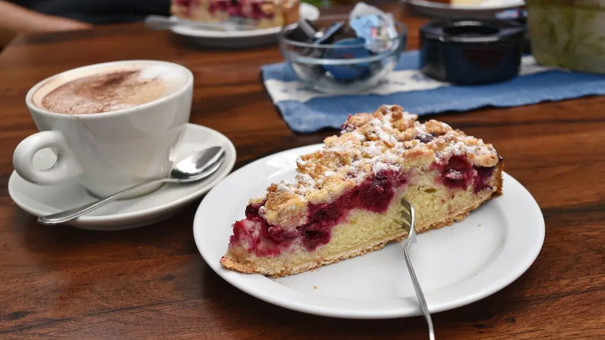 Ein Stück Kirsch-Streuselkuchen und ein Cappuccino.