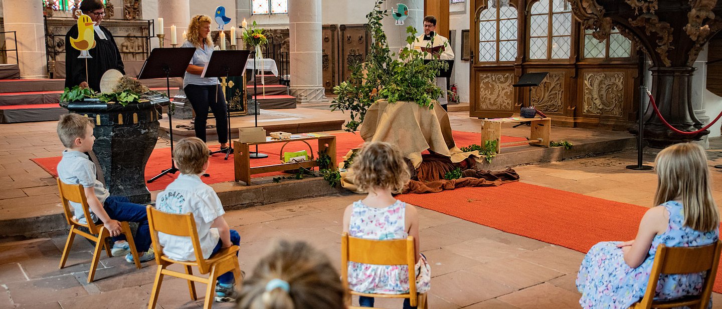 Kinder sitzen während dem Einschulungsgottesdienst in einem Stuhlkreis vor dem Altar.