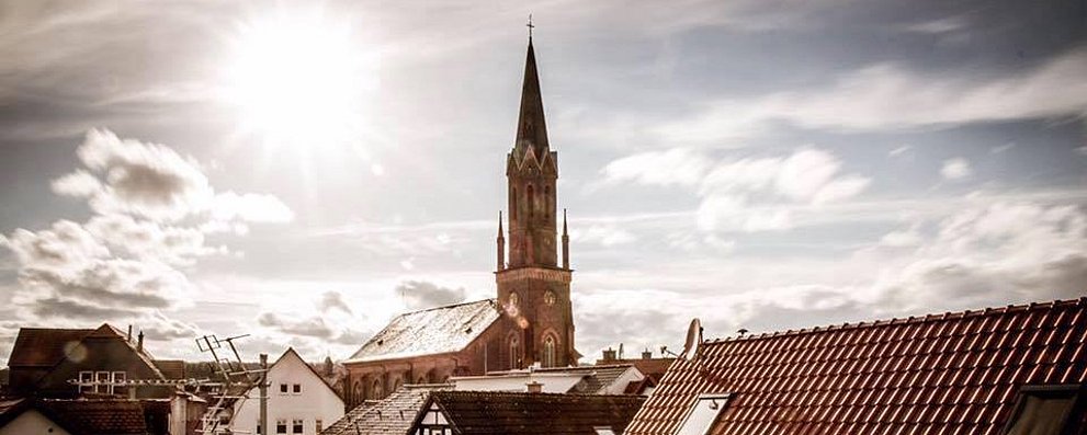 Seulberger Kirchturm über den Dächern des Ortes im Gegenlicht.