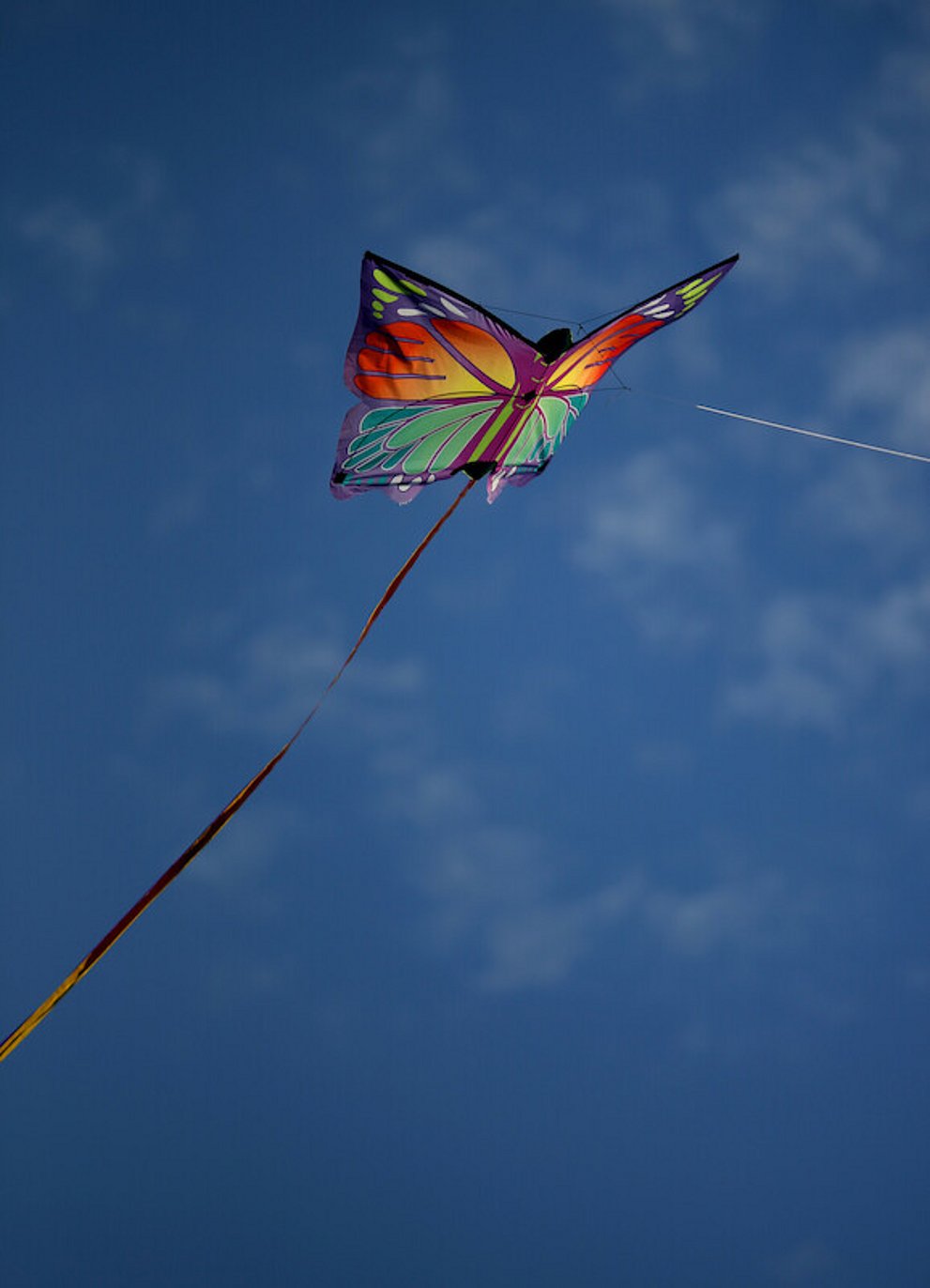 Ein Bunter, Schmetterling Flugdrache fliegt vor einem blauen Himmel.