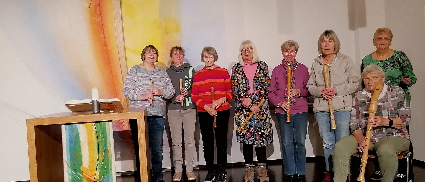 Gruppe von 9 Frauen stehen vor einem Altar mit Flöten in der Hand