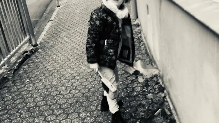 Das schwarz-weiß Foto zeigt 1 KiTa - Kind bei der "Hausmeister" - Arbeit vor der KiTa.