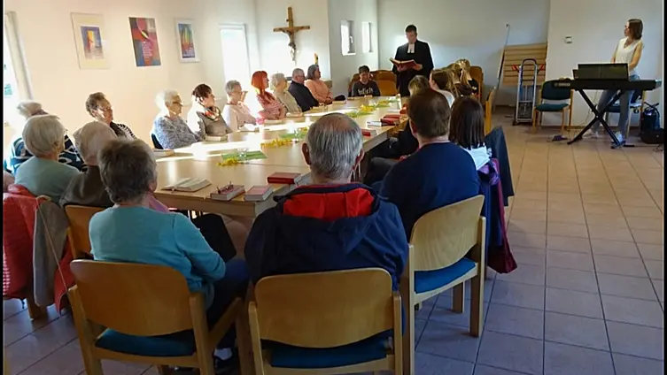 Das Foto zeigt etwa 25 Menschen beim gemeinsamen Tischabendmahl.