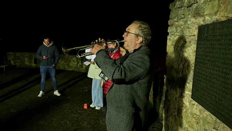 Der Pfarrer bläst während einer nächtlichen Andacht auf einer Trompete