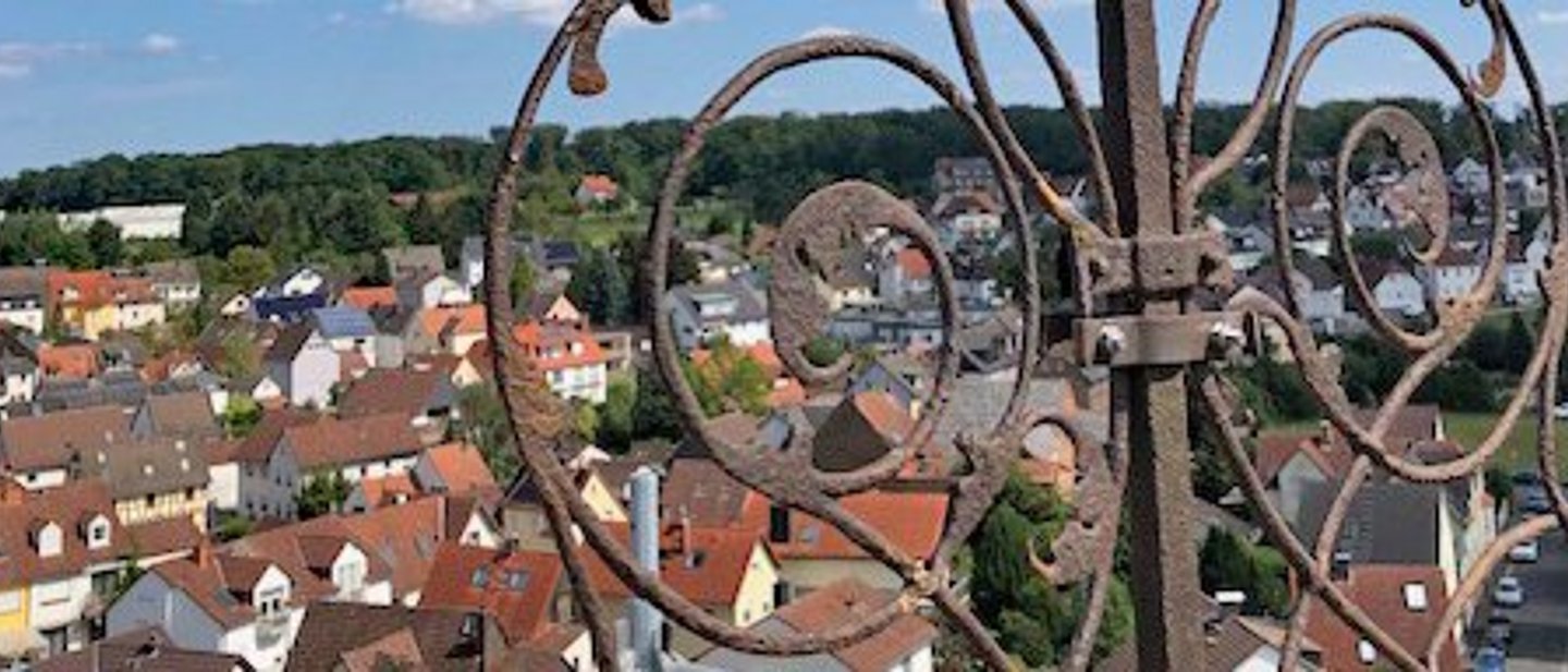 Blick von der Kirchturmspitze der evangelischen Kirche Köppern auf den Ort während der Dachsanierung. Im Vordergrund ein Teil des Turmkreuzes mit vergoldetem Wetterhahn.