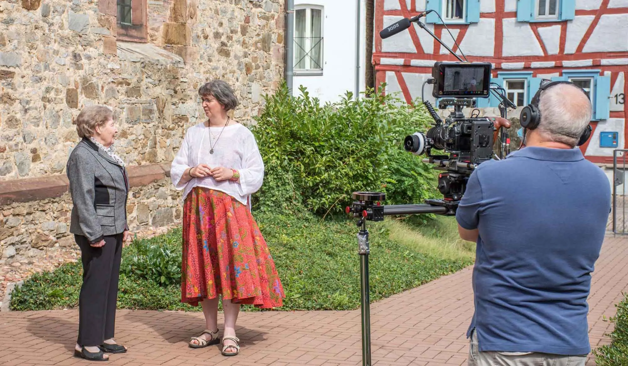 Dreharbeiten zu einem Film über die evangelische Kirche Burgholzhausen. Das Bild zeigt Mariane Peilstöcker im Gespräch mit Friedrichsdorfs Stadtführerin Karin Halfmann. Rechts der Kameramann bei den Aufnahmen. 