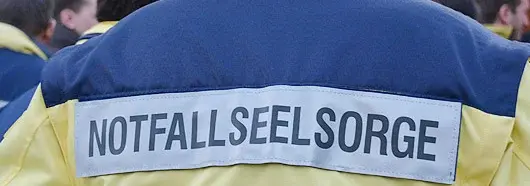 Der Rücken einer Person einer Person ist zu sehen. Auf ihrer Jacke steht "Notfallseelsorge".