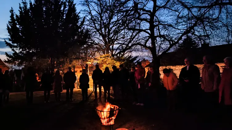 Menschen die früh Morgens um eine Osterfeuer stehen