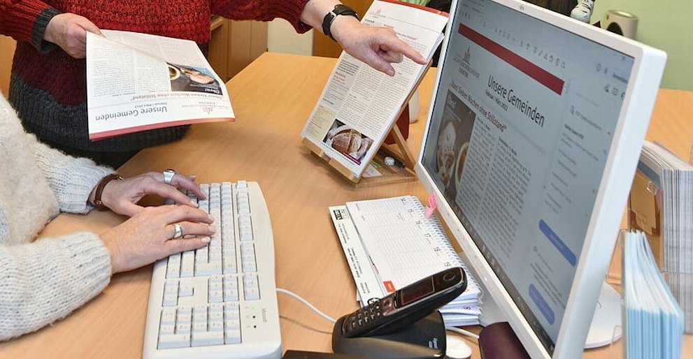 Zwei Frauen von der ehrenamtlichen Redaktion besprechen eine Ausgabe der Zeitschrift "Unsere Gemeinde".