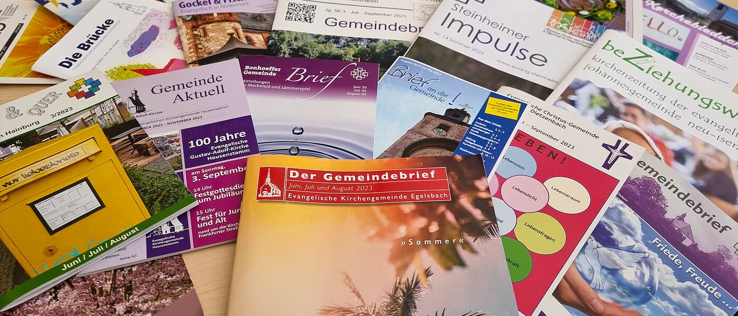 Man sieht viele unterschiedliche Gemeindebriefe in verschiedenen Formaten, Farben und Gestaltungen