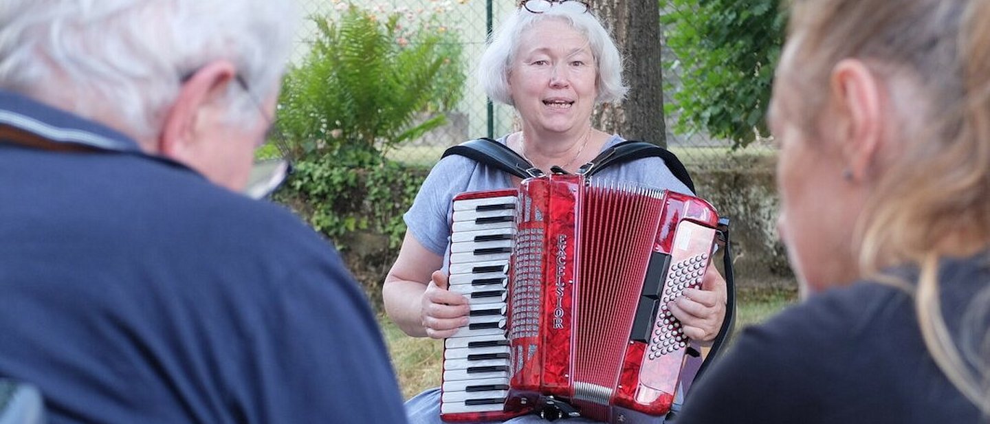 Dorothee Ewald spielt Akkordeon die Besucher*innen des Treffs.