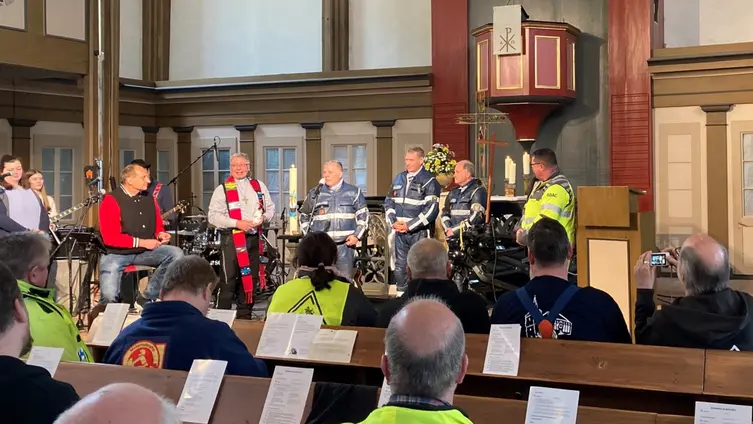 Vor dem Altar steht ein Pfarrer mit Stola und mehrere Polizisten in ihrer Uniform für das Motorrad 