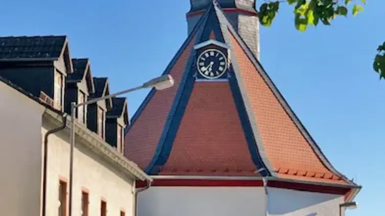 Dorfbarockkirche Köppern, Straßenansicht von hinten, Blick auf den Chor mit rotem Biberschwanzdach, Rundfenster und Uhr unterhalb des Chordachabschlusses.