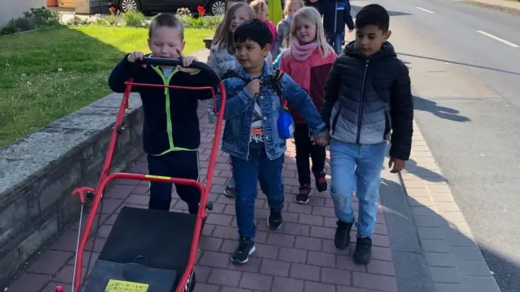 Die KiTa-Kinder mit dem Rasenmäher auf dem Weg in den KiTa-Garten.