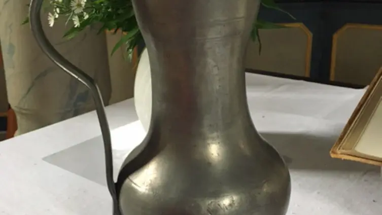 Ein Weinkanne aus Zinn in der evangelischen Kirche Köppern - auf dem aufklappbaren Deckel die Jahreszahl 1694.