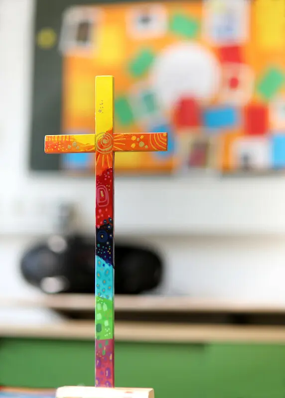 buntes Holzkreuz auf Tuch auf einem Tisch.