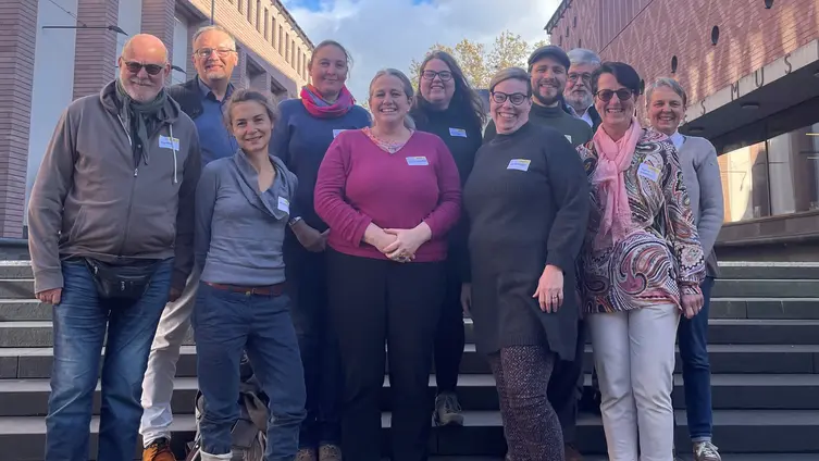 Gruppenfoto von 15 Personen auf einer Treppe