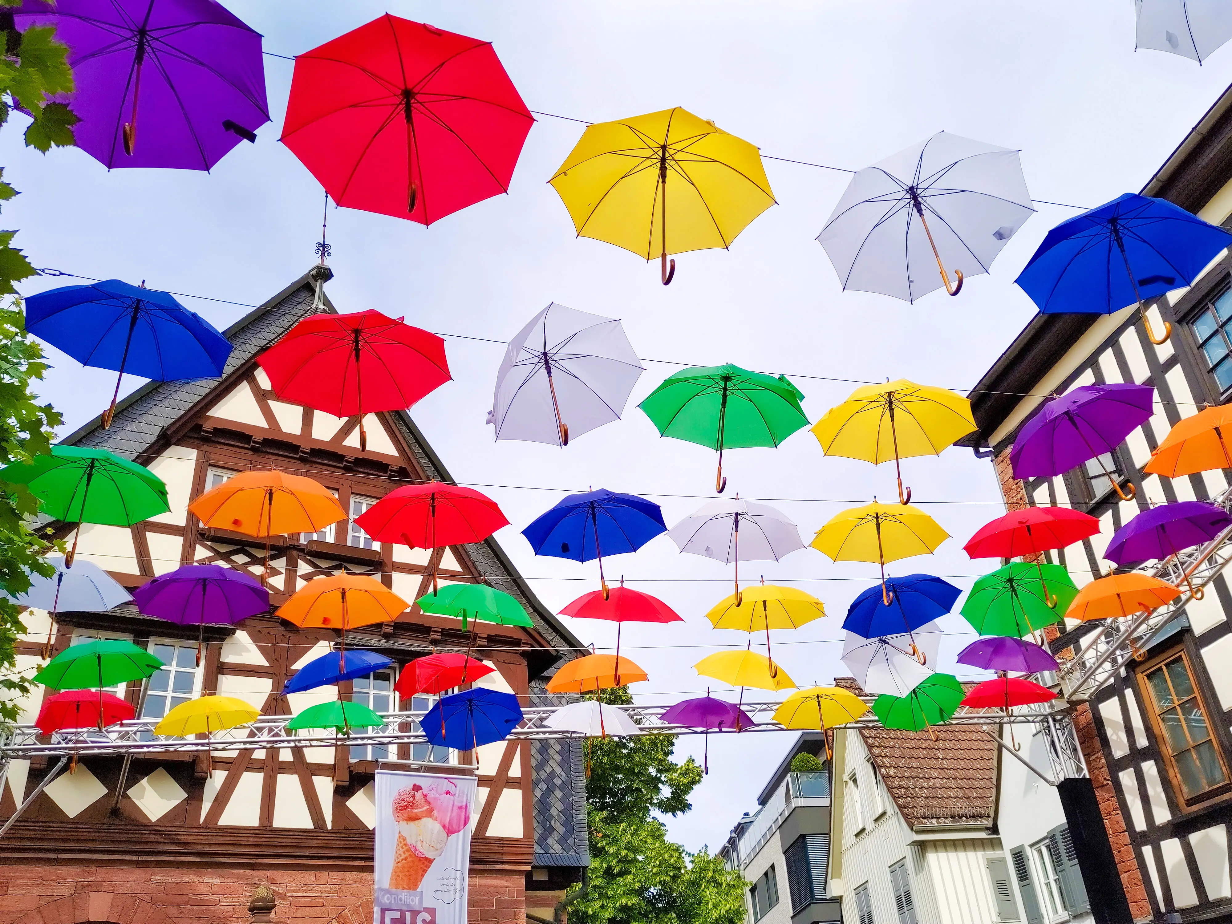 Fachwerkhäuser in Hofheim mit bunten Regenschirmen, die an Seilen zwischen den Häusern gespannt sind