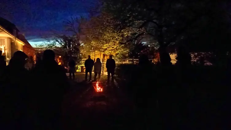 eine Gruppe von menschen trifft sich vor Sonnenaufgang im Garten der Kirche um eine Osternachtsliturgie zu feiern 