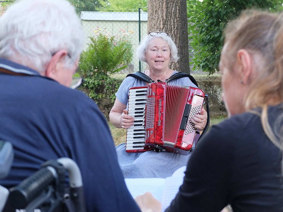 Dorothee Ewald spielt Akkordeon die Besucher*innen des Treffs.