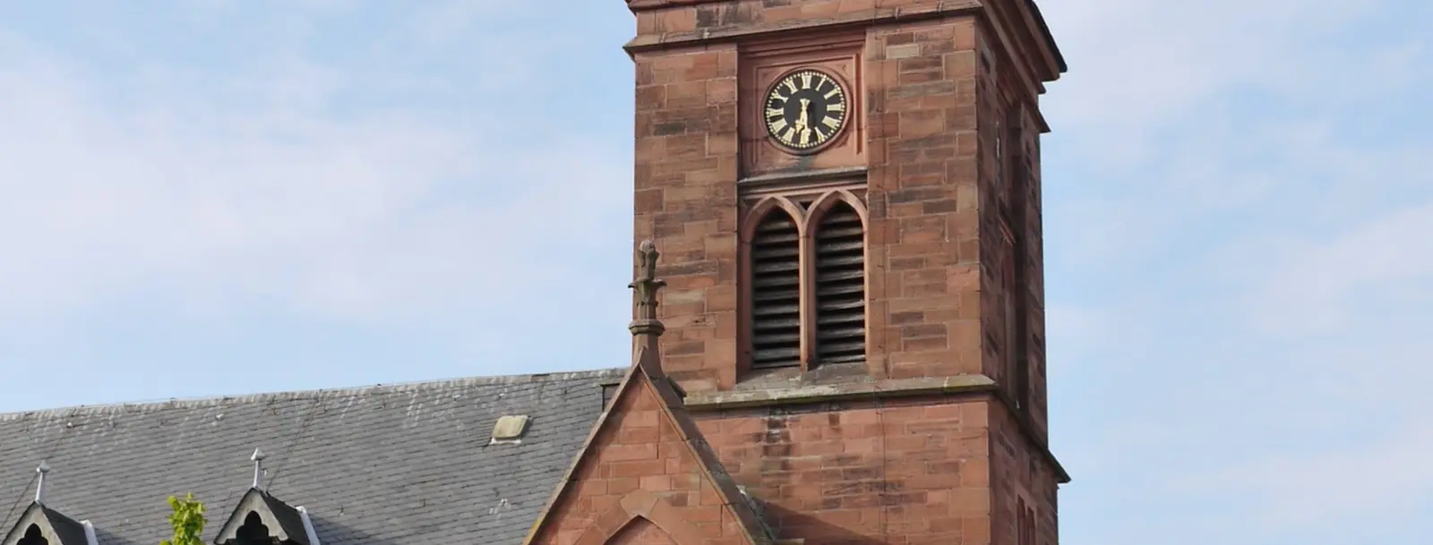 Ein Kirchturm mit Uhr vor blauem Himmel