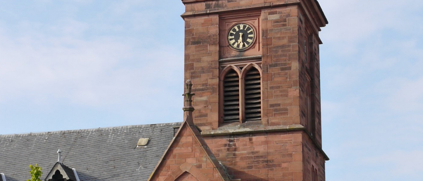 Ein Kirchturm mit Uhr vor blauem Himmel