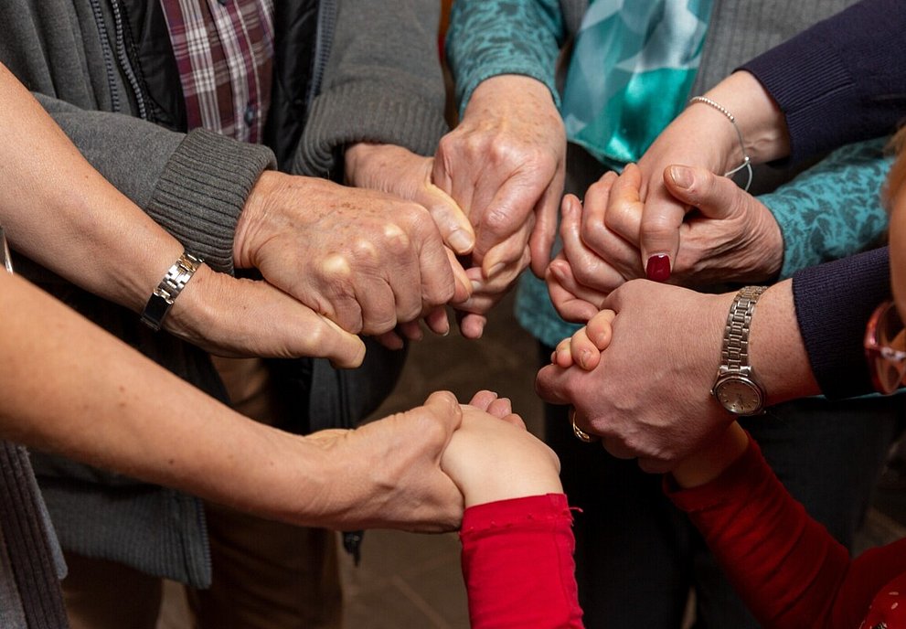 Gruppe Betender, die sich an den H#nden halten.