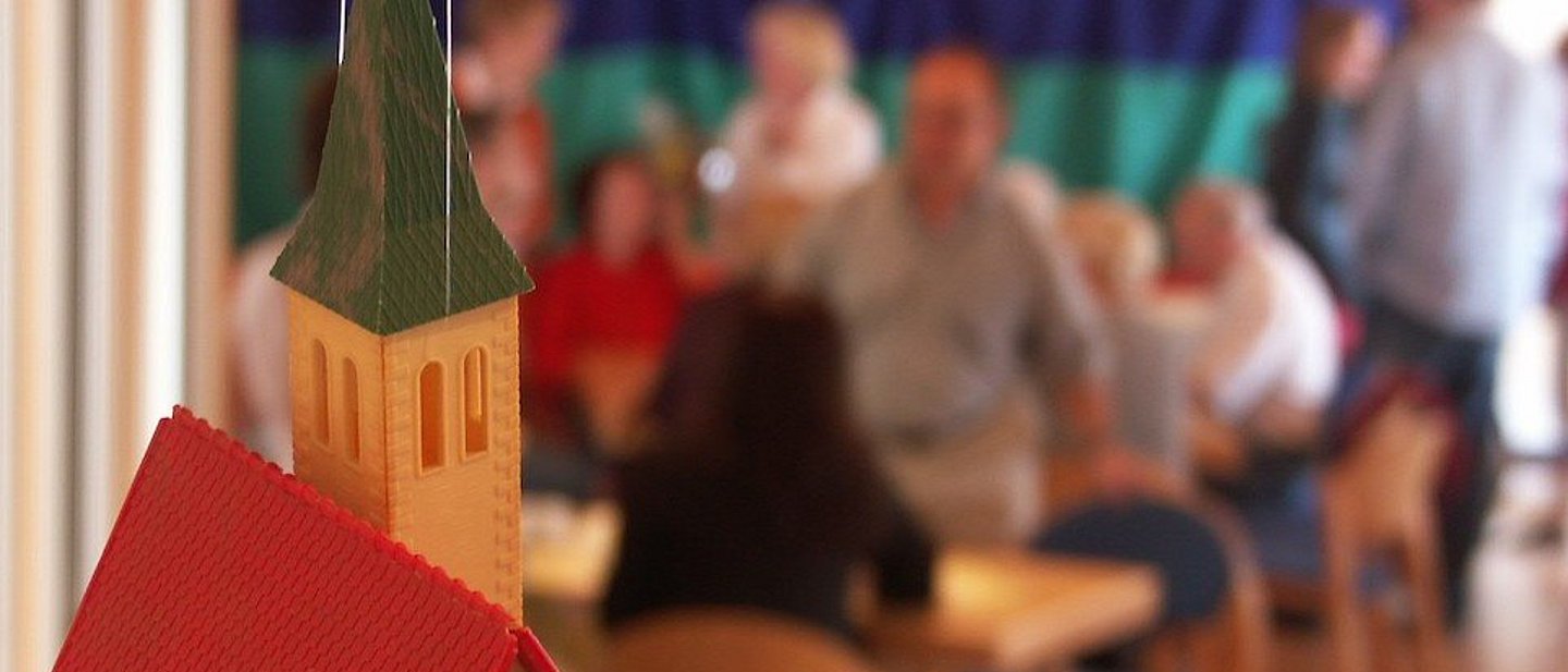 Modell einer Kirche mit Menschen im Hintergrund