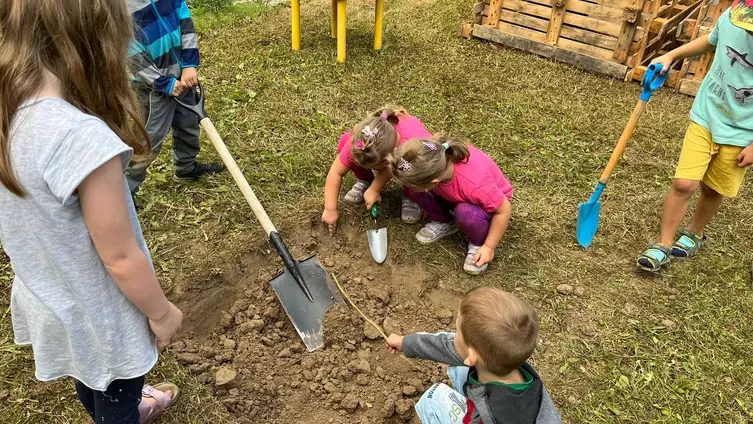Auf den Fotos sieht man die Kinder und ErzieherInnen des "Haus des Kindes" beim Anlegen einer Feuerstelle und 2 Hochbeeten in ihrem Garten.